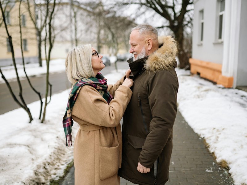 Couple with jackets scarves snow on ground