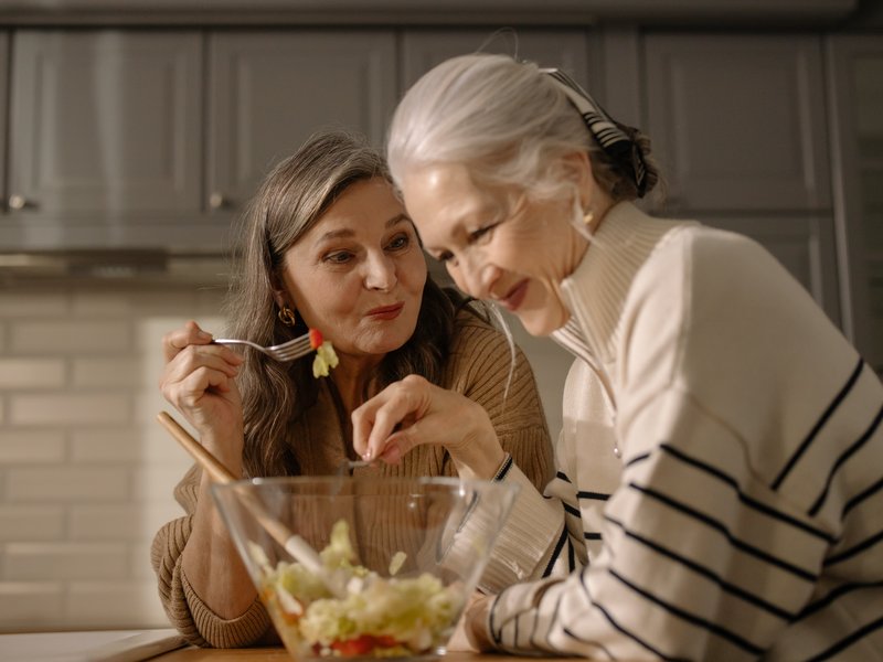 Two women eating in kitchen